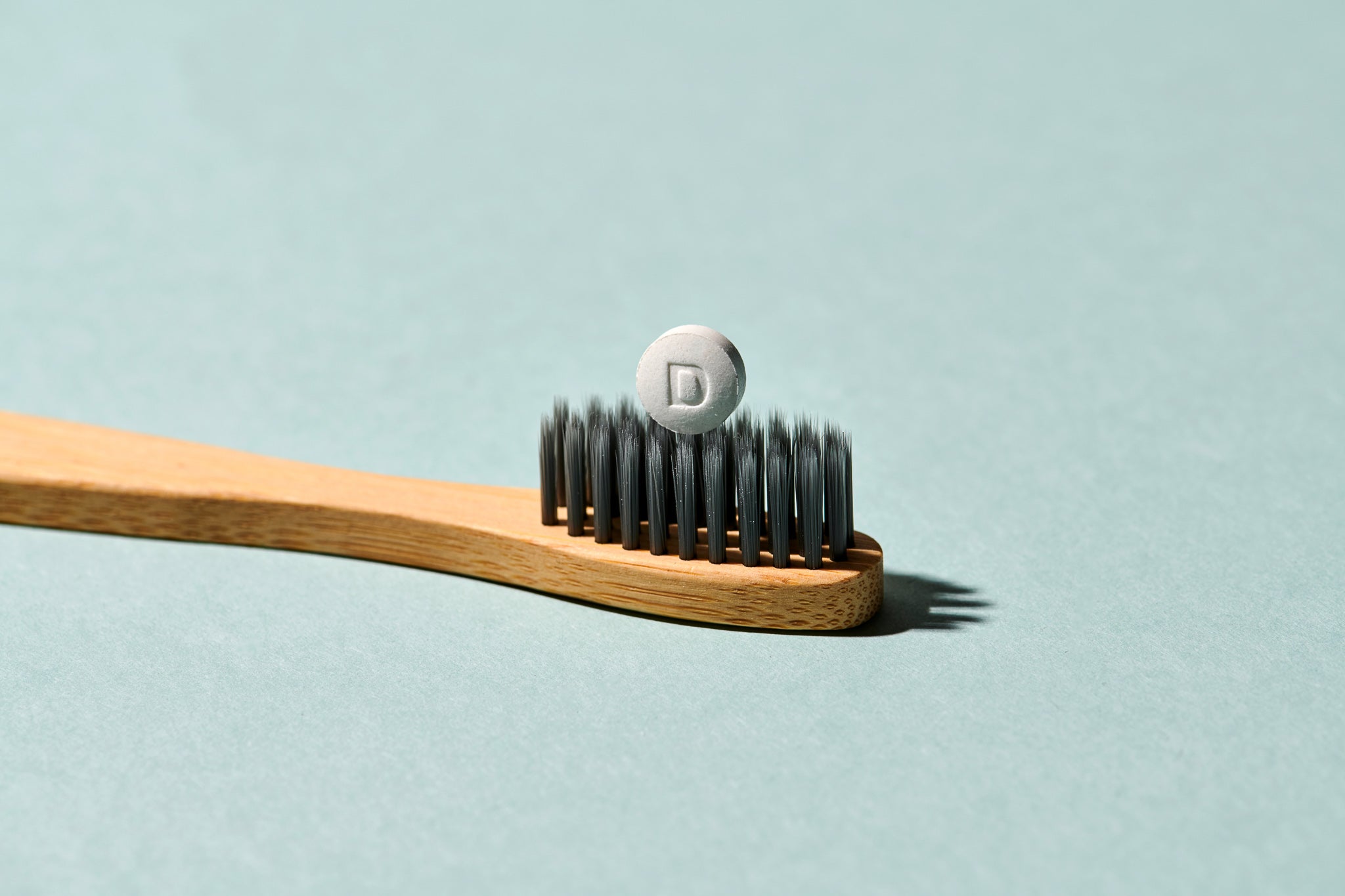 Denttabs Bambuszahnbürste mit einer Zahnpastatabletteauf den schwarzen Borsten