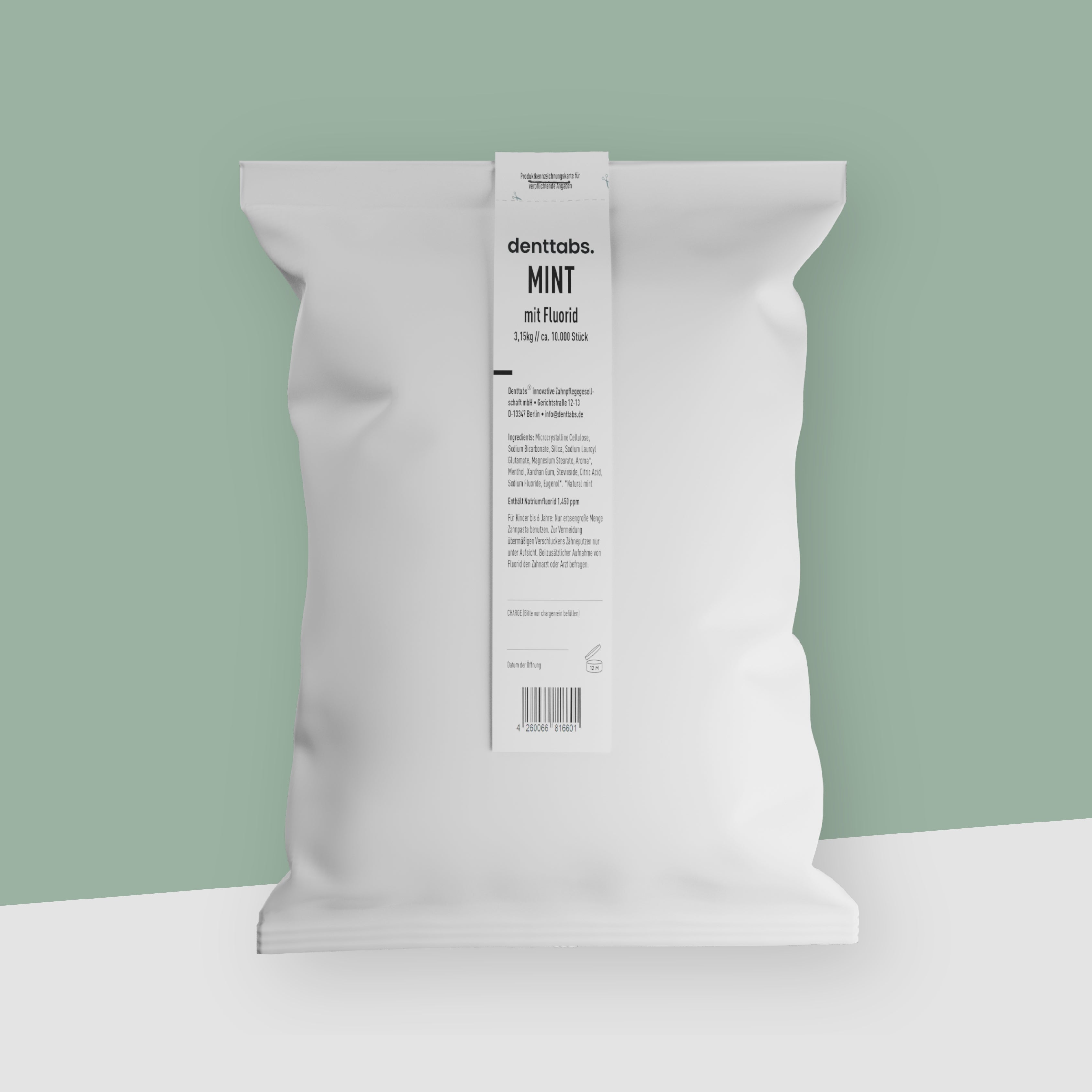 Ein weißer Beutel voll mit 1 Kilogramm Zahnputztabletten vor einem pastellgrünen Hintergrund.