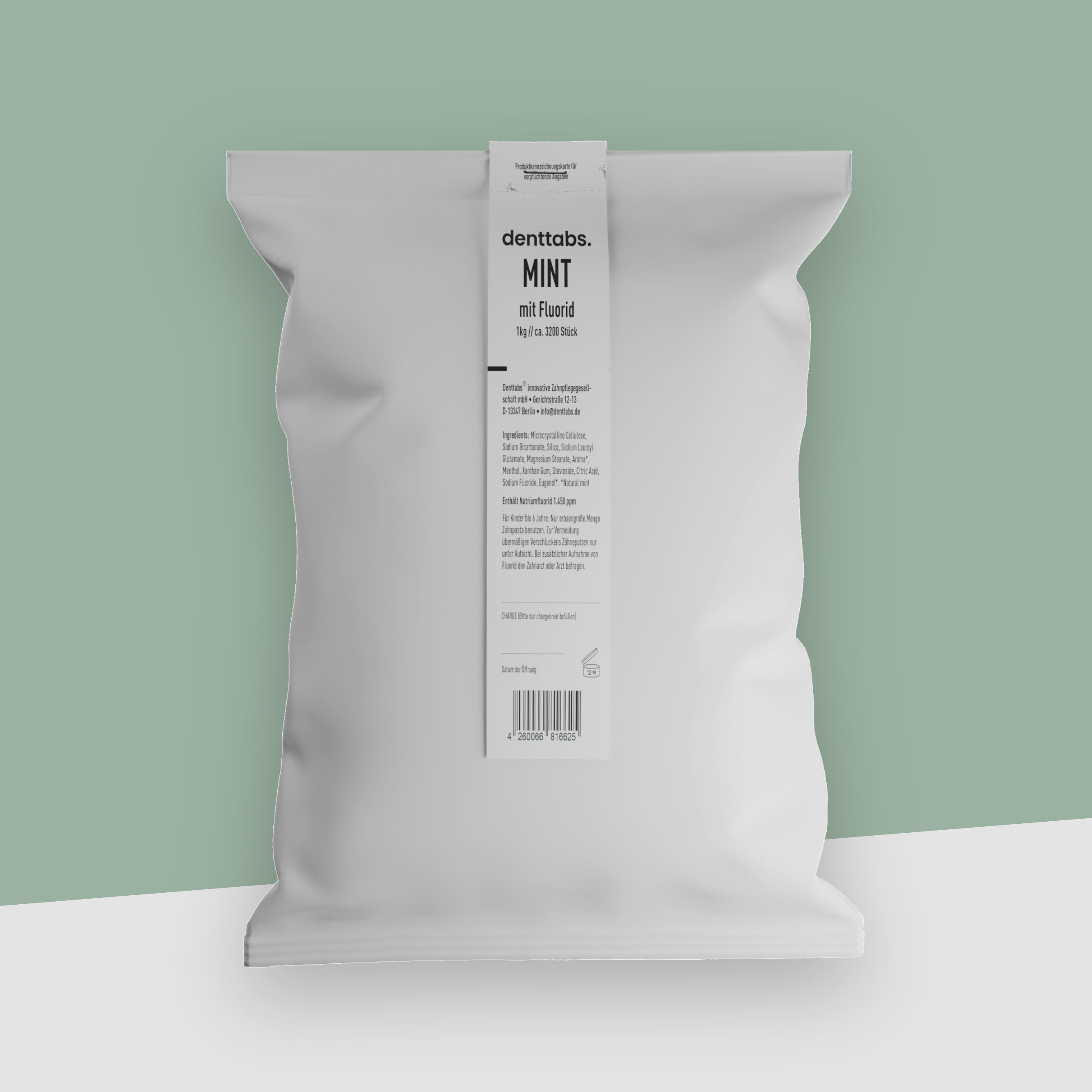 Ein weißer Beutel voll mit 1 Kilogramm Zahnputztabletten vor einem pastellgrünen Hintergrund.